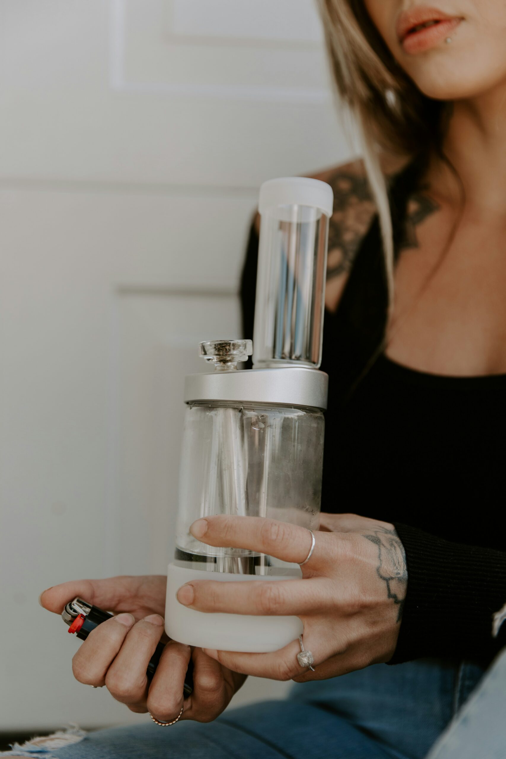 Close-up of hands assembling a glass bottle with a white cap and metal mechanism.